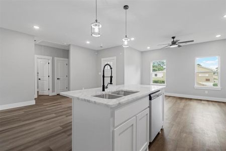 Kitchen featuring decorative light fixtures, dark hardwood / wood-style flooring, dishwasher, a center island with sink, and sink