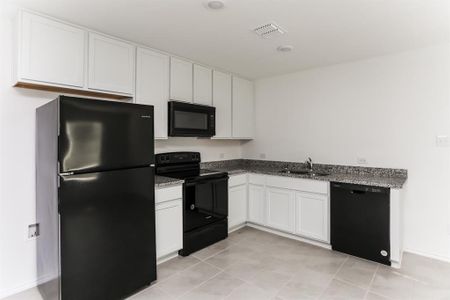 Kitchen with light granite counters, sink, white cabinetry, and black appliances