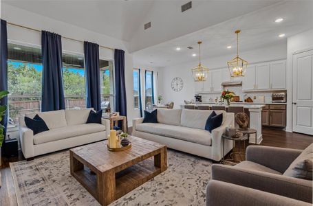 Living room with a chandelier, high vaulted ceiling, and light wood-type flooring