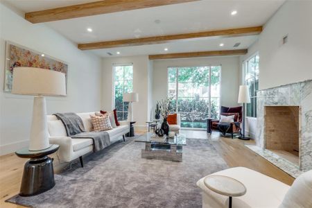 Living room with a premium fireplace, beam ceiling, and light hardwood / wood-style flooring