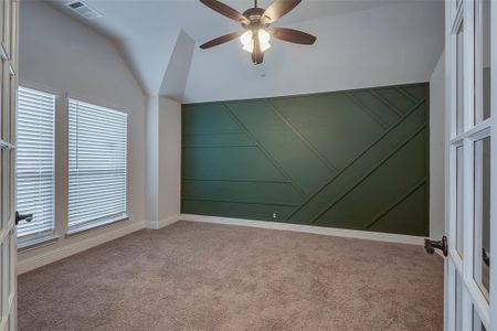 Spare room featuring vaulted ceiling, light carpet, and ceiling fan