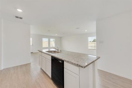 Kitchen with light hardwood / wood-style floors, black dishwasher, sink, and an island with sink