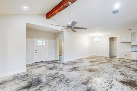 Unfurnished living room featuring vaulted ceiling with beams and ceiling fan with notable chandelier