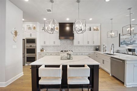 Kitchen with custom range hood, a center island, stainless steel appliances, and sink