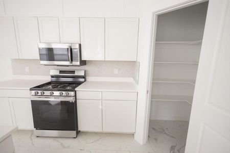 Kitchen with stainless steel appliances, white cabinets, tasteful backsplash, and light tile floors