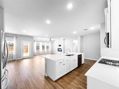 Kitchen with stainless steel appliances, sink, white cabinetry, hardwood / wood-style flooring, and a spacious island