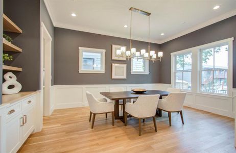 Dining room is filled with natural light, painted in a beautiful grey, floating shelves, and a beautiful chandelier.