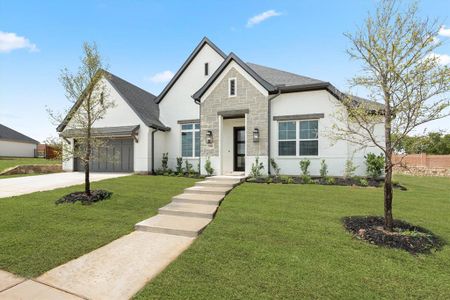 French country inspired facade featuring a garage and a front lawn