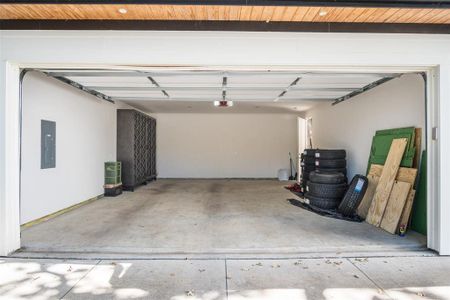 Garage featuring wood ceiling, a garage door opener, and electric panel