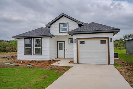 View of front of home featuring cooling unit, a garage, and a front lawn