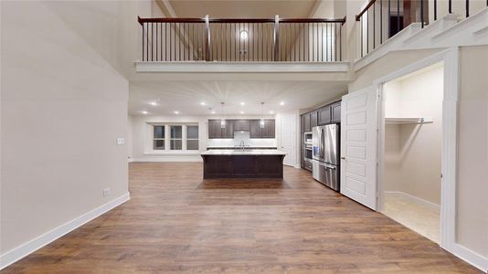 Kitchen featuring hardwood / wood-style flooring, stainless steel fridge with ice dispenser, an island with sink, and a high ceiling