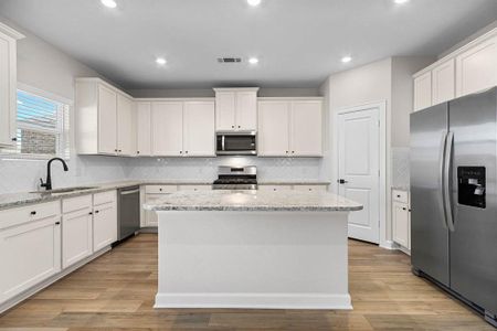 The neutral palette of white cabinets, stainless steel appliances, and granite countertops offers a versatile foundation for personalization and decor accents, allowing homeowners to easily adapt the kitchen's aesthetic to suit their individual tastes and preferences.