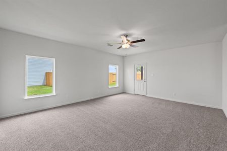 Carpeted living room with ceiling fan and plenty of natural light