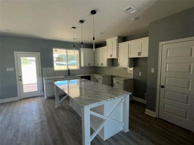 Kitchen with tasteful backsplash, white cabinets, sink, a kitchen island, and dark hardwood / wood-style flooring