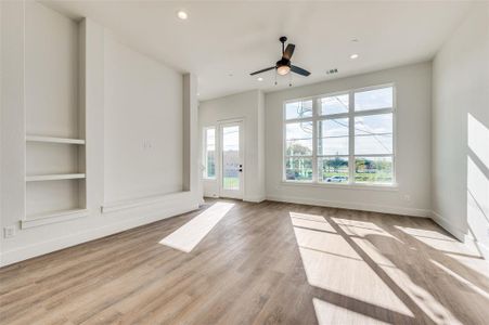 Spare room with built in features, ceiling fan, and light hardwood / wood-style flooring