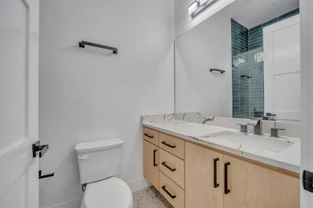 Bathroom with toilet, vanity, and tiled shower