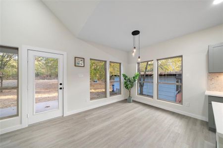 Unfurnished dining area featuring light hardwood / wood-style flooring, vaulted ceiling, and a wealth of natural light