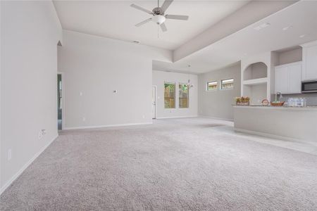 Unfurnished living room featuring light colored carpet and ceiling fan