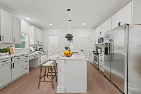 Kitchen with a kitchen island with sink, light hardwood / wood-style flooring, white cabinetry, and stainless steel appliances