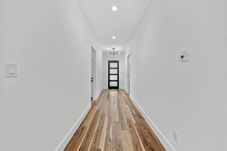 Hall with light hardwood / wood-style floors and an inviting chandelier