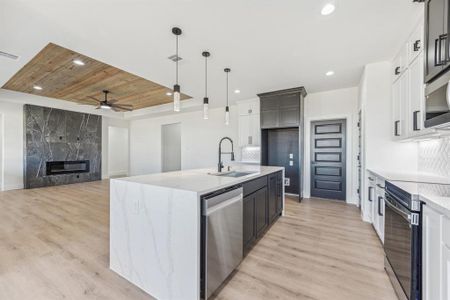 Kitchen with a kitchen island with sink, pendant lighting, stainless steel appliances, and light hardwood / wood-style flooring