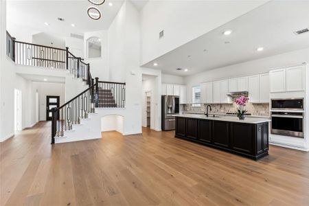 Kitchen featuring light hardwood / wood-style floors, a kitchen island with sink, stainless steel appliances, and white cabinets