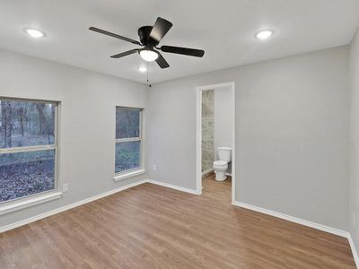 Unfurnished bedroom with light wood-type flooring, ceiling fan, and ensuite bathroom