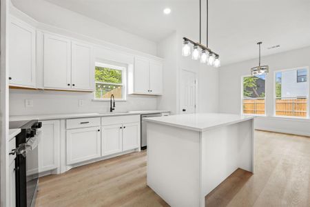 Kitchen with white cabinetry, light wood-type flooring, a center island, stainless steel appliances, and decorative light fixtures
