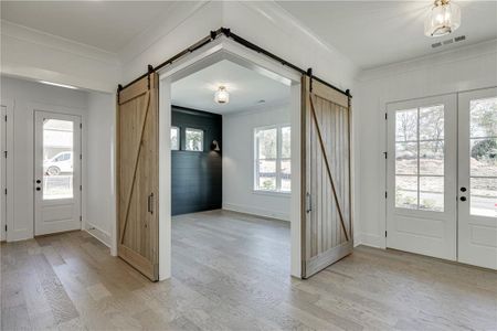 Foyer featuring a barn door, crown molding, and light hardwood / wood-style floors