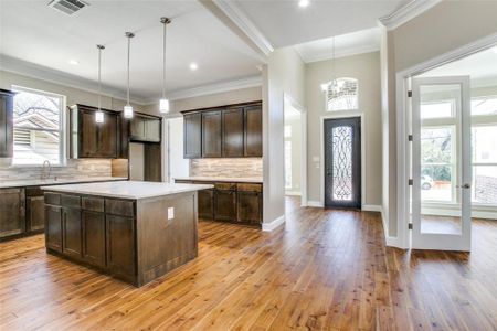 Kitchen with a healthy amount of sunlight, a kitchen island, decorative backsplash, and light hardwood / wood-style floors