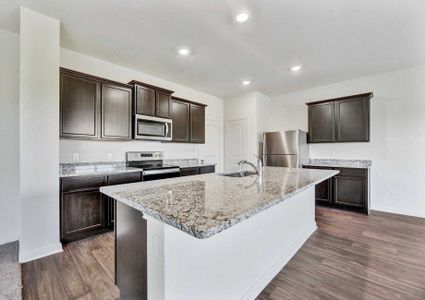 Rio kitchen with recessed lights, large granite kitchen island, and brown custom cabinets