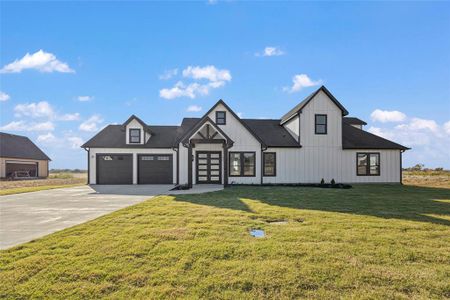 Modern farmhouse featuring a front lawn and a garage