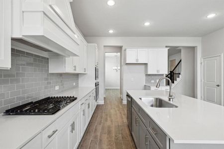 Kitchen with appliances with stainless steel finishes, custom range hood, white cabinetry, dark wood-type flooring, and sink