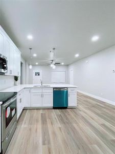 Kitchen featuring ceiling fan, decorative light fixtures, appliances with stainless steel finishes, and white cabinetry