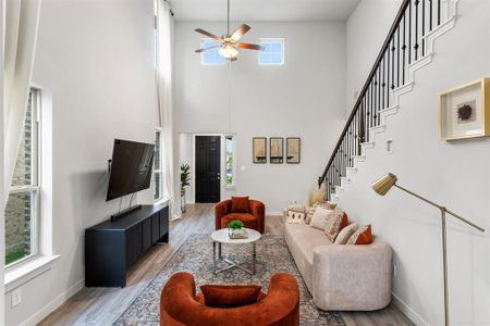 Living room featuring ceiling fan, a towering ceiling, and hardwood / wood-style floors