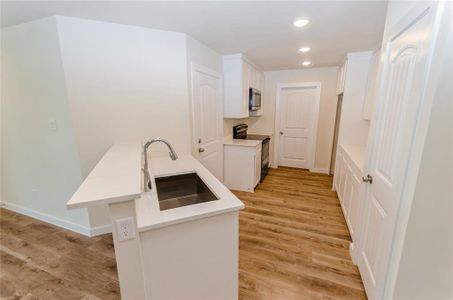 Kitchen featuring light hardwood / wood-style floors, sink, white cabinetry, and electric range oven