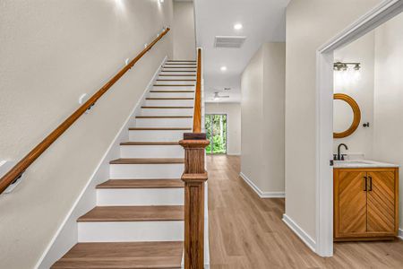 First floor entry with powder room to the right, stained wood accented stairway and living space beyond.