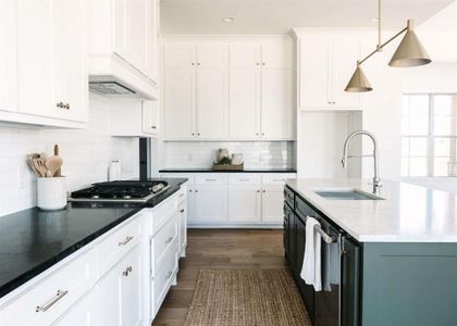 Kitchen featuring dark wood-type flooring, white cabinets, sink, hanging light fixtures, and stainless steel appliances