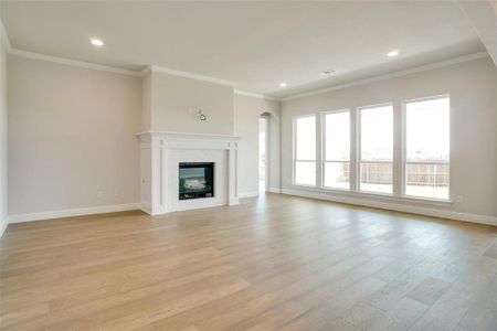 Unfurnished living room featuring light hardwood / wood-style flooring and ornamental molding