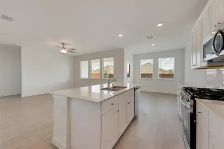 Kitchen with an island with sink, decorative backsplash, sink, white cabinetry, and appliances with stainless steel finishes