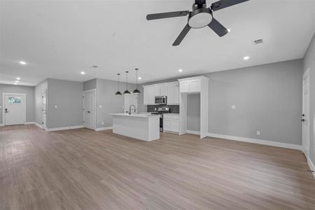 Unfurnished living room featuring ceiling fan and light hardwood / wood-style floors