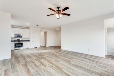 Unfurnished living room featuring ceiling fan and light hardwood / wood-style flooring