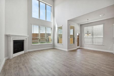 Unfurnished living room with a high ceiling, light hardwood / wood-style floors, and an inviting chandelier