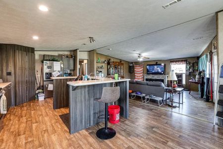 Kitchen with a breakfast bar, a textured ceiling, stainless steel fridge with ice dispenser, light hardwood / wood-style flooring, and a center island with sink