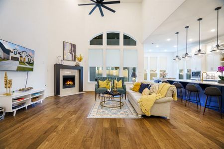 Living room with ceiling fan, a towering ceiling, and wood-type flooring