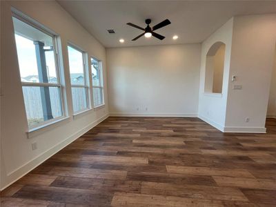 Large family room with vinyl plank flooring, light floods in with large windows, 10' ceilings and a ceiling fan.