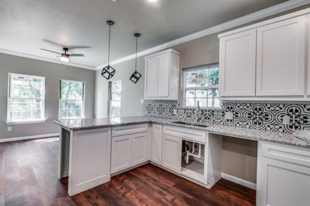 Kitchen featuring dark wood-type flooring, ceiling fan, white cabinetry, and sink