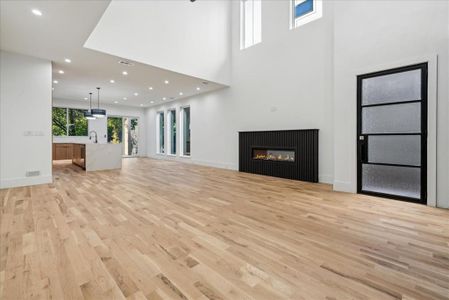 Unfurnished living room with light wood-type flooring, a towering ceiling, and sink