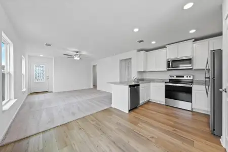 Kitchen includes granite countertops, luxury vinyl plank flooring, 36” upper cabinets with crown molding, a full suite of stainless-steel Whirlpool appliances – including refrigerator with ice maker, recessed lighting, and a large single basin sink.