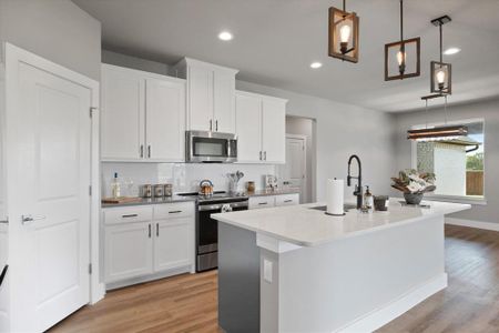 Kitchen featuring white cabinetry, an island with sink, pendant lighting, stainless steel appliances, and light wood-type flooring